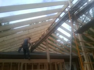 Rafters going up over a new addition with a worker on the wall in Senoia