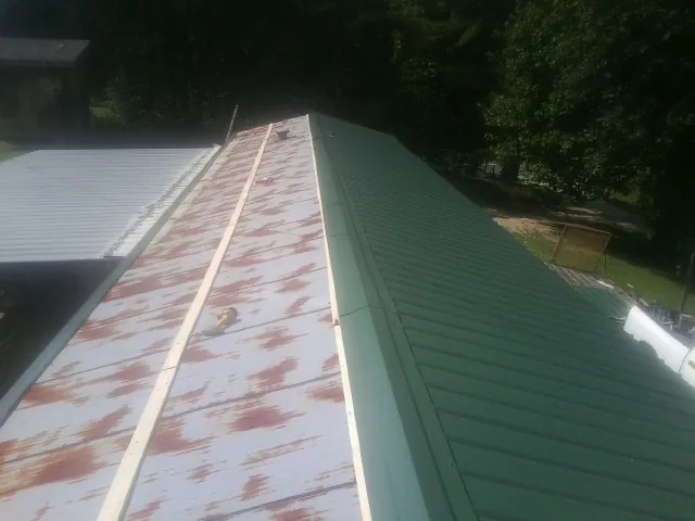 Old rusted panels beside newly installed green metal roofing — Wind Damage Roof Repair by Roofing Brothers in Senoia