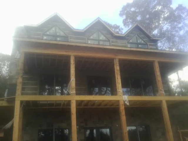 Dormers and porch framing on a large log home under construction — Roof Coating work by our crew in Senoia