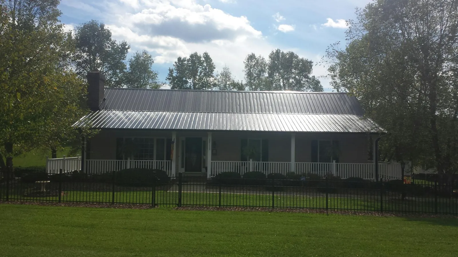Gray metal roof on a brick ranch with a full width front porch — Gutter Guard Installation work by our crew in Senoia