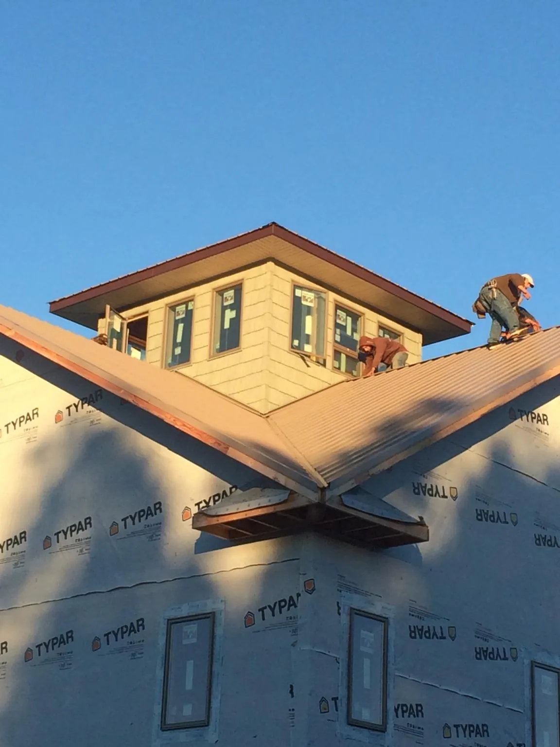 Roofers working around a rooftop cupola on a new metal roof at sunset — Roof Waterproofing in Senoia by Roofing Brothers